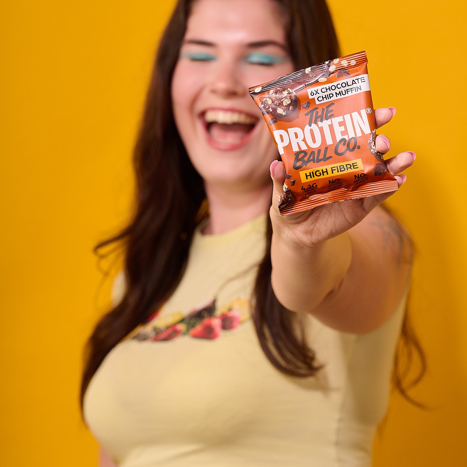 Protein ball snack bag with 6x chocolate muffin flavor, held by a person