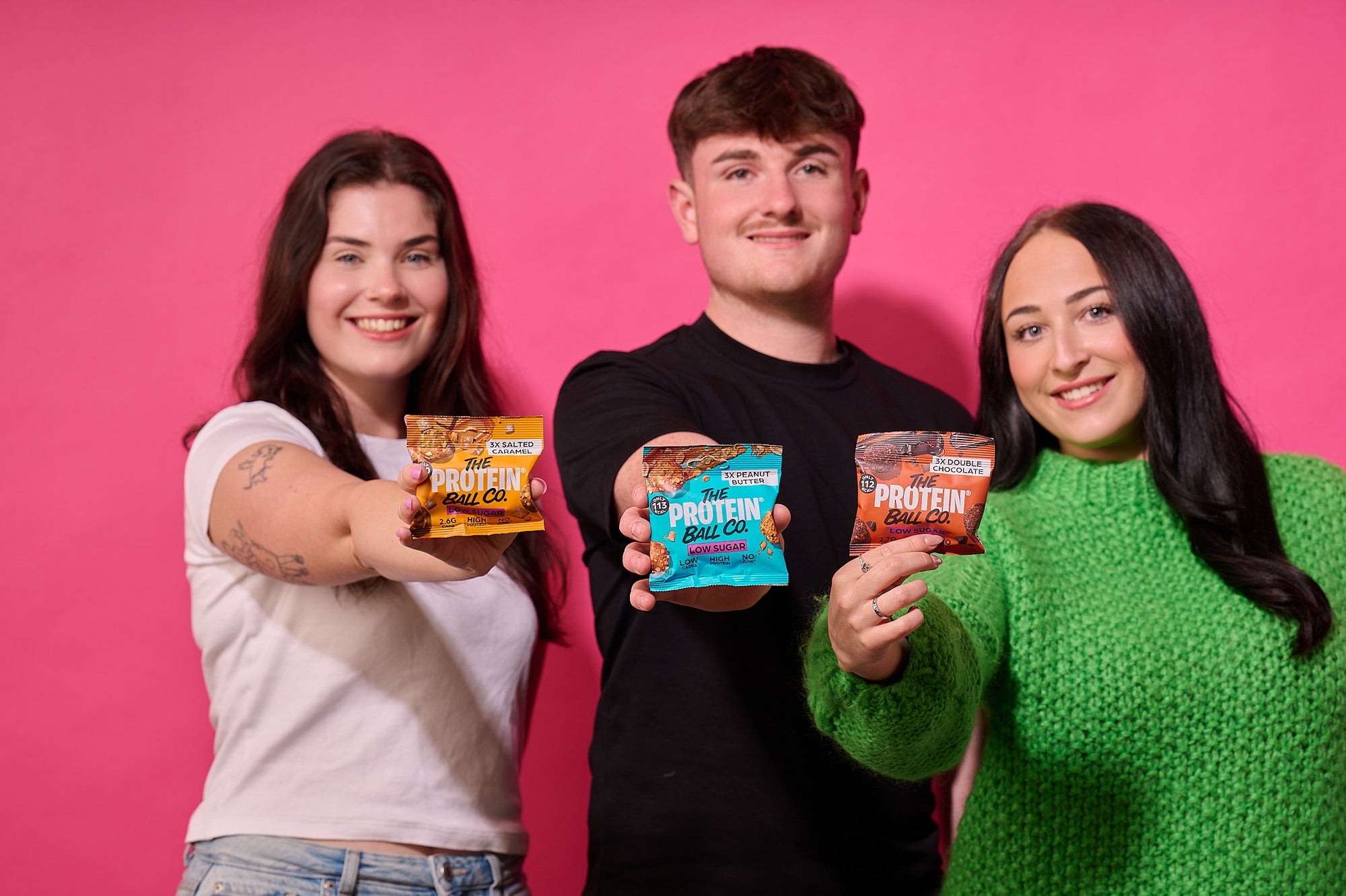 People holding The Protein Ball Co low sugar protein ball bags
