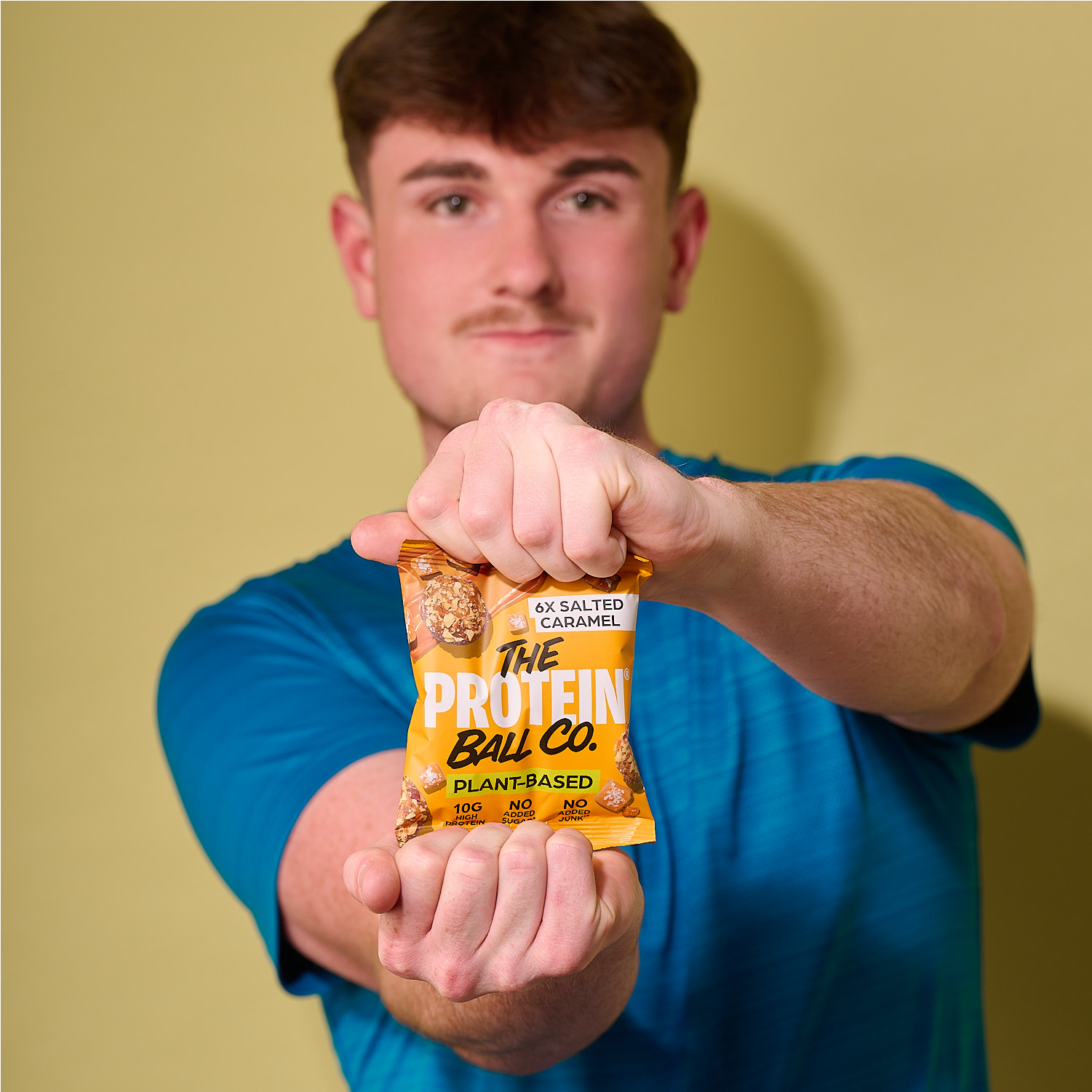 Person holding a salted caramel plant-based protein ball bag, front label centered.
